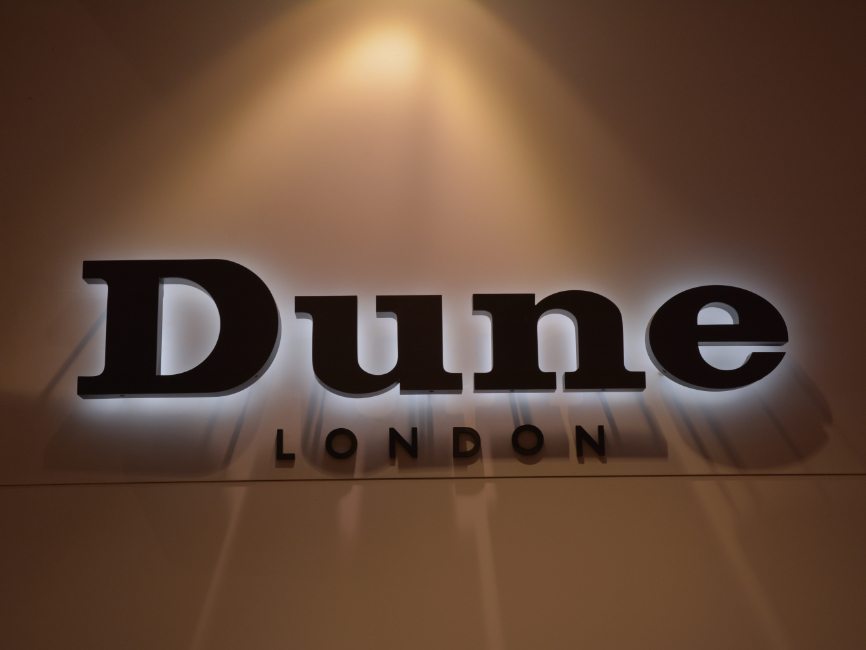 gallery image of custom retail interior project featuring custom backlit logo for Dune of London by Visual Millwork