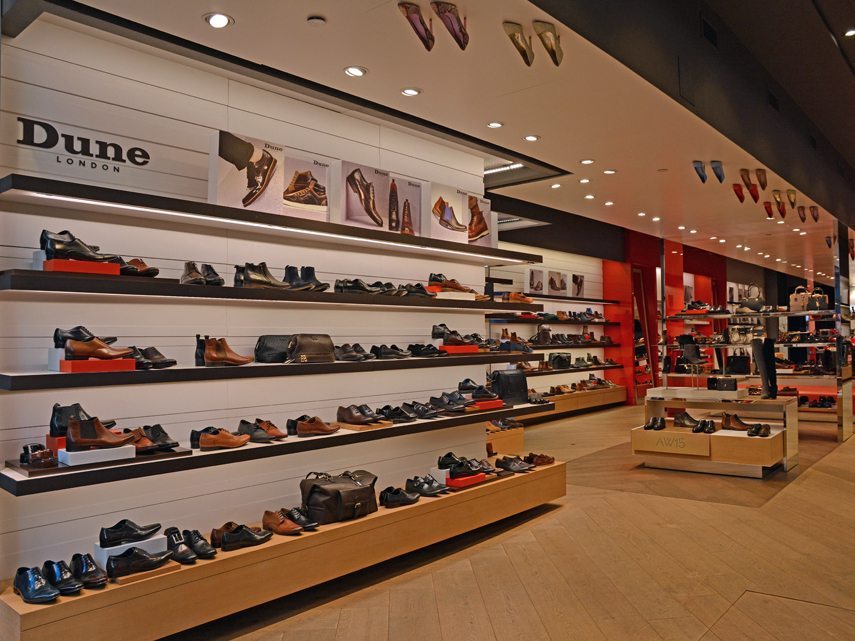 gallery image of custom retail interior project featuring custom LED illuminated shoe wall, ceiling suspended shoe display, custom shoe displays and fixtures for Dune of London by Visual Millwork