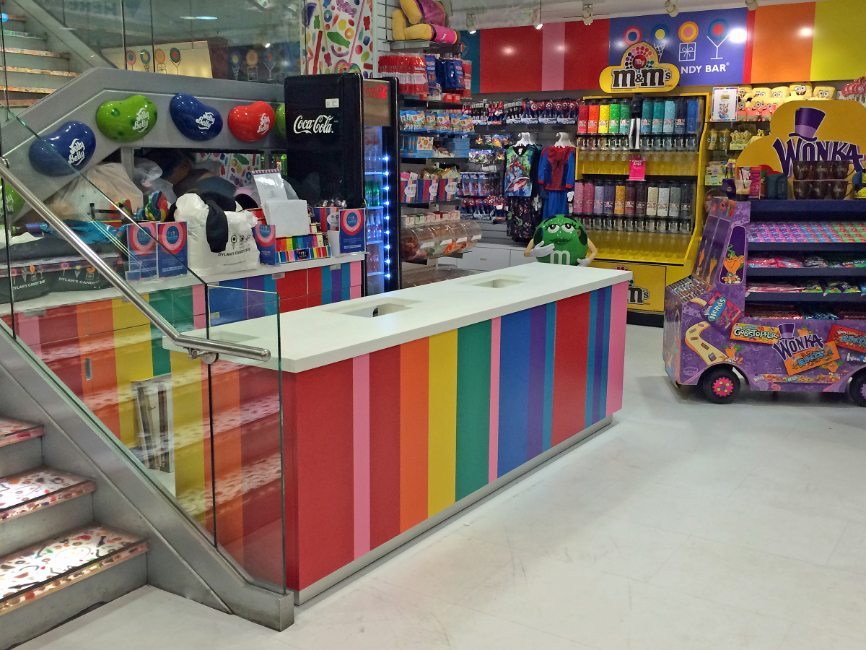 gallery image of custom retail interior finishes and components project featuring custom designed  striped formica back warp with cabinets and drawers for Dylan's Candy Bar by Visual Millwork