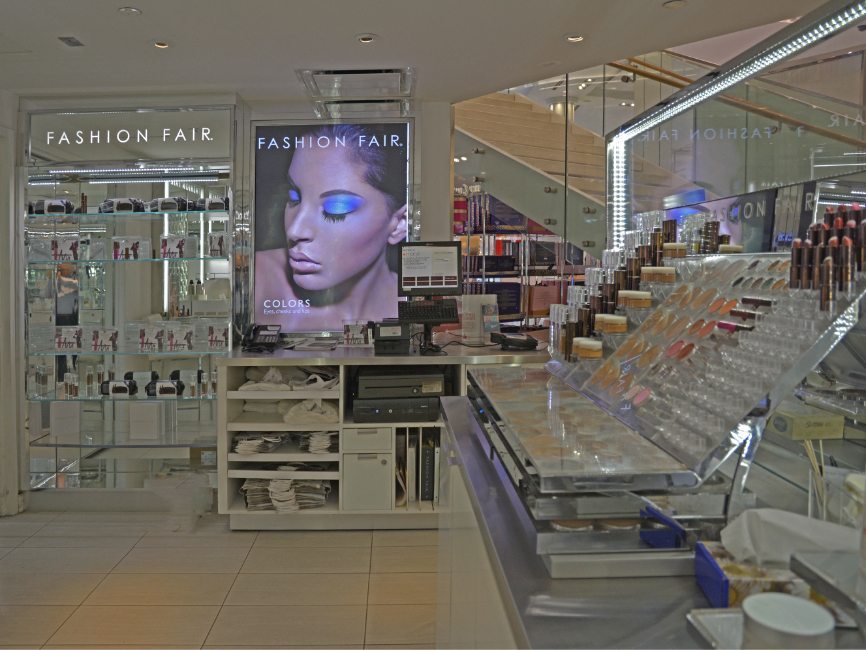 gallery image of custom retail interior in-store display make-up boutique rpoject featuring LED display signage, custom make-up display fixtures and custom perimeter shelving for Fashion Fair at Macy's by Visual Millwork