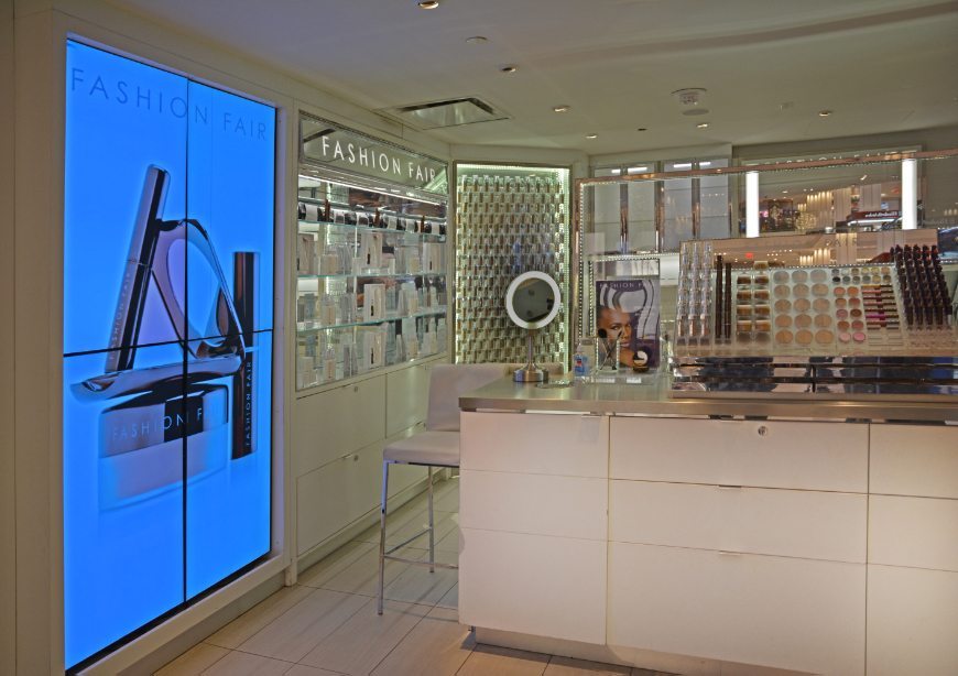 gallery image of custom retail interior in-store display featuring LED display signage, custom display counter with storage drawers, and custom LED make-up display walls for Fashion Fair at Macy's by Visual Millwork