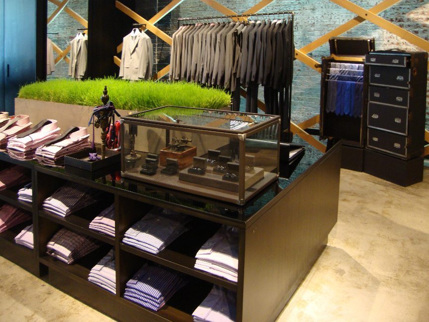 gallery image of custom retail interior clothing store featuring custom secure showcase, custom shirt display counter with shelves, custom clothing rack, custom tie display  trunk and custom display trunk with drawers for Hugo Boss by Visual Millwork