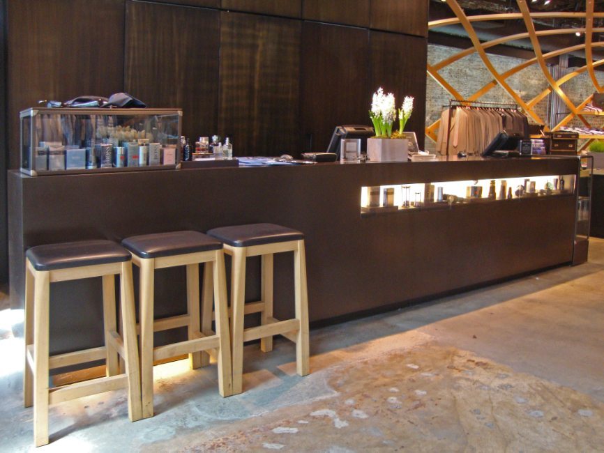 gallery image of custom retail interior clothing store featuring custom counter and seating, and custom wood veneer wall paneling for Hugo Boss by Visual Millwork